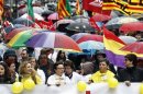 People hold umbrellas as they march with a banner during a protest against government austerity measures in Barcelona