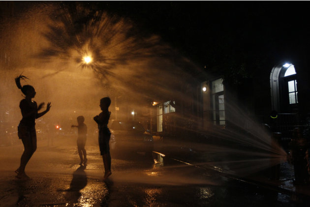 Vanity Mendez, 11, left, Isaiah Rivera, 6, center,  and Jonathan Medina, 11, cool off at an open fire hydrant in the East Village neighborhood of Manhattan, Thursday, July 21, 2011.  A heatwave that h