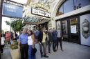 People pose for photographs before entering the Capitol Theatre to see "The Book of Mormon" musical Tuesday, July 28, 2015, in Salt Lake City. The biting satirical musical that mocks Mormons has finally come to the heart of Mormonlandia, starting a sold-out, two-week run Tuesday at the Salt Lake City theater two blocks from the church's flagship temple and headquarters. (AP Photo/Rick Bowmer)