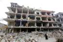A woman walks past a damaged building in the Douma neighbourhood of Damascus