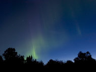 Una aurora boreal es visible sobre las copas de los árboles en Nikiski, Alaska, el sábado 6 de agosto de 2011, debido a las tormentas solares ocurridas a principios de semana. El avistamiento de auroras continuará en los próximos días. (AP foto/Peninsula Clarion, M. Scott Moon)