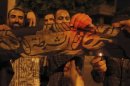 Islamist protesters shout slogans and burn a flag, after they took it down and erected several al Qaeda flags at the main door of the state security headquarters in Cairo