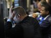 A trader places his hand on his face next to other traders working on the floor of the New York Stock Exchange