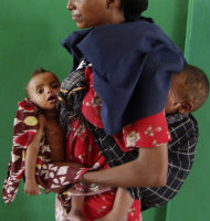 A woman from southern Somalia holds her malnourished children at Banadir hospital in Mogadishu, Somalia, Tuesday, Aug. 2, 2011. The United Nations says famine will probably spread to all of southern Somalia within a month and force tens of thousands more people to flee into the capital of Mogadishu. (AP Photo/Farah Abdi Warsameh)