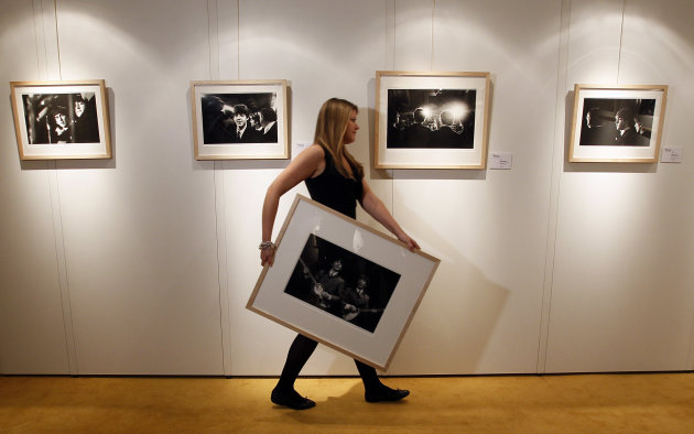 A Christie's employee carries Mike Mitchell's photograph of The Beatles, where this collection is being exhibited at a hotel in London, Friday, June 10, 2011. The previously unseen photographs by US p