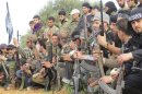 Free Syrian Army fighters carry their weapons as they sit in attention during the declaration of the formation of Al-Liwaa brigade in Binnish