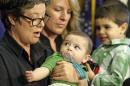 FILE - In this Feb. 28, 2014, file photo, Kathy Harbin, left, and her spouse Michelle Call hold their children Louis Harbin-Call, 6 months, and Leo Harbin-Call, 2, as they speak during a news conference, at the Utah State Capitol, in Salt Lake City. More than 1,000 same-sex married couples in Utah must wait longer for state benefits after the U.S. Supreme Court granted the state a stay on an order requiring it to recognize the marriages. (AP Photo/Rick Bowmer, File)