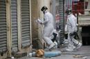 Forensic experts enter a building as they work on the scene in Saint-Denis the day after a police raid to catch fugitives from Friday night's deadly attacks in the French capital