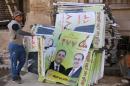 An Iraqi employee of a printing house puts together campaign posters showing former Baghdad governor Salah Abdul Razzaq and Iraqi Prime Minister Nuri al-Maliki (R) on March 31, 2014 in the Iraqi capital