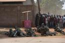 Residents look on as French soldiers hold their position on a Bangui street after hearing gunshots on December 20, 2013