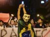 A demonstrator wearing a Guy Fawkes mask takes photos on her mobile phone during a protest in central Rio de Janeiro