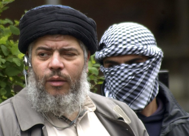 FILE - This Friday, April 30, 2004 file photo shows Muslim cleric Abu Hamza al-Masri, as he arrives with a masked bodyguard, right, to conduct Friday prayers in the street outside the closed Finsbury Park Mosque in London. Al-Masri pleaded not guilty Tuesday, Oct, 9, 2012 to charges that he conspired with Seattle men to set up a terrorist training camp in Oregon. Al-Masri entered the plea shortly before U.S. District Judge Katherine B. Forrest set an Aug. 26 trial date for al-Masri. (AP Photo/Max Nash, File)