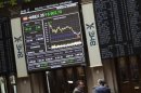 Traders talk as the IBEX 35 session is displayed on an electronic board at Madrid's stock exchange