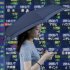 A woman holding a parasol walks past an electronic stock board of a securities firm in Tokyo Friday, Aug. 3, 2012. Japan's Nikkei 225 stock average was down 1.2 percent at 8,553.68 on Friday as Asian stock markets fell after the European Central Bank's policy meeting failed to deliver on bold promises of action to overcome the region's prolonged debt crisis. (AP Photo/Koji Sasahara)