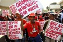 Protesters carry placards as they protest against the visit of U.S. President Obama in Pretoria