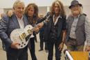 FILE - In this Oct. 8, 2013 file photo released by Uruguay's Press Office, President Jose Mujica, left, poses with Aerosmith's band members Steven Tyler, second from left, Joe Perry, second from right, and Brad Whitford after receiving an autographed guitar as a gift at presidential house in Montevideo, Uruguay. While outside his country he is an international figure, well known for his modest lifestyle, consistent with his ideals and his good-nature, among his own people Uruguay's President known as "Pepe" does not generate such devotion and many question his management. (AP Photo/Uruguay Press Office, Alvaro Salas, File)