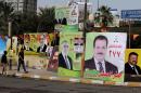 People walk past election campaign posters in Baghdad, Iraq, Friday, April 4, 2014. The election campaign kicked off Tuesday with Iraqi towns and cities flooded with posters of the candidates for parliament seats on main streets and intersections. (AP Photo/Karim Kadim)