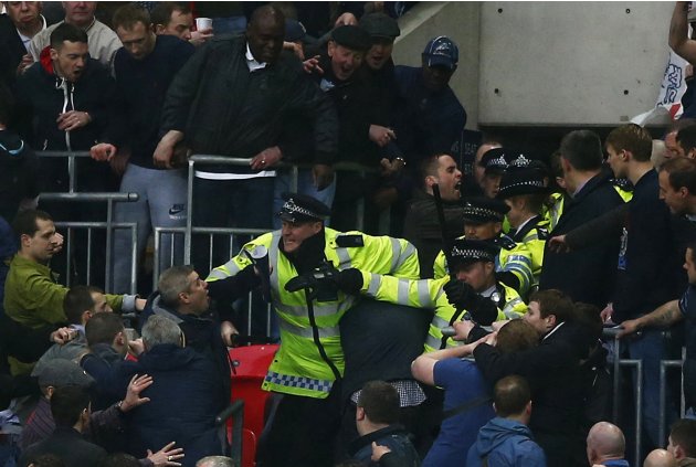 Millwall fans fight with police officers during FA Cup semi-final soccer match against Wigan Athletic at Wembley Stadium in London