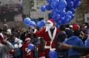 A Palestinian dressed as Santa Claus holds balloons at Manger Square, outside the Church of the Nativity, traditionally believed by Christians to be the birthplace of Jesus Christ, in the West Bank city of Bethlehem on Christmas Eve Wednesday, Dec. 24, 2014. (AP Photo/Majdi Mohammed)