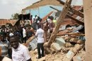 People gather outside the ruins of a church targeted by a suicide bombing in a church in Jos