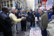 An exchange of opinions between a supporter of the Occupy Wall Street protests, right, and passersby attracts attention at Zuccotti Park in New York on Tuesday, Oct. 25, 2011. Some businesses and residents are losing patience with the protesters in the park, the unofficial headquarters of the movement that began in mid-September. (AP Photo/Bebeto Matthews)