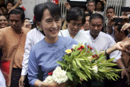 Myanmar opposition leader Aung San Suu Kyi, center, is greeted by supporters as she arrives to attend the opening ceremony of a branch office of her National League for Democracy (NLD) party on Tuesday, May 8, 2012, in Yangon, Myanmar. (AP Photo/Khin Maung Win)