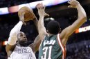 LeBron James del Heat de Miami dispara a la canasta ante John Henson de los Bucks de Milwaukee en los playoffs de la NBA el martes 23 de abril de 2013. (AP Foto/Wilfredo Lee)