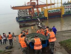 Rescue workers carry a boat for a search after a ship sank at the Jianli section of Yangtze River