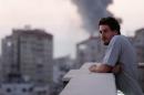 This photo taken in August, 2014 shows Associated Press video journalist Simone Camilli on a balcony overlooking smoke from Israeli Strikes in Gaza City. Camilli, 35, was killed in an ordnance explosion in the Gaza Strip, on Wednesday, Aug. 13, 2014 together with Palestinian translator Ali Shehda Abu Afash and three members of the Gaza police. Police said four other people were seriously injured, including AP photographer Hatem Moussa.(AP Photo/Lefteris Pitarakis)