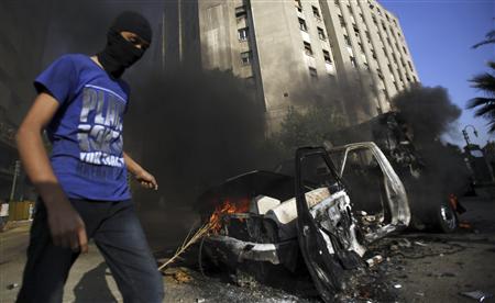 A protester walks after he set fire to a police vehicle during clashes with riot police along a road which leads to the U.S. embassy, near Tahrir Square in Cairo September 13, 2012. Egypts President Mohamed Mursi said on Thursday he supported peaceful protest but not attacks on embassies, after Egyptians angry at a film deemed insulting to the Prophet Mohammad climbed into the U.S. embassy in Cairo and tore down the U.S. flag. He pledged to protect foreigners in Egypt. REUTERS/Amr Abdallah Dalsh