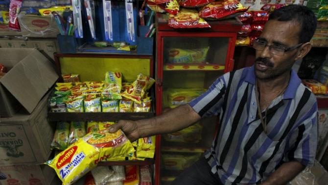 A vendor sells a Maggi noodles packet to a customer inside a grocery shop in Kolkata