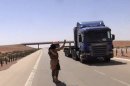 This undated image made from video posted on a militant website in Aug. 2013, with is consistent with other AP reporting, purports to show a jihadi militant flagging down a truck on a major highway in western Iraq. The video shows militants stopping three Syrian truck drivers, interrogating them, then gunning them down, believing them to be members of the Alawite sect. The incident, as well as another posted video of a mob stringing up a suspected terrorist's shirtless body by the feet and set it ablaze on a street on the outskirts of the Iraqi capital, both confirmed by police, illustrate in stark terms the increasing brutality of the unrest gripping Iraq, fueling complaints that security forces are unable to contain it. (AP Photo via militant website)