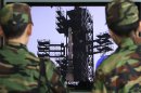 South Korean Army soldiers watch a TV news program which shows North Korea's Unha-3 rocket at Seoul train station in Seoul, South Korea, Monday, April 9, 2012. North Korean space officials moved all three stages of the long-range rocket into position for a controversial launch, vowing Sunday to push ahead with their plan in defiance of international warnings against violating a ban on missile activity. (AP Photo/Ahn Young-joon)
