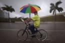 An umbrella vendor rides his bike up the flooded Biscayne Blvd in Miami
