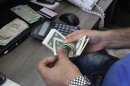 In this photo taken on Wednesday, Oct. 24, 2012, a currency exchange bureau worker counts U.S. dollars in downtown Tehran, Iran. Iranian authorities have been forced to quell protests in recent weeks over the plummeting value of the country's currency which lost nearly 40 percent of its value against the U.S. dollar in a week in early October. With the U.S. election less than 10 days away, both President Obama and Republican challenger Mitt Romney are cautious about discussing potential compromises as Iran's economy shows signs of increasing strain from economic sanctions that seek nuclear concessions. (AP Photo/Vahid Salemi)