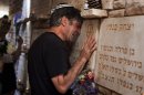 An Israeli man cries beside a memorial stone for a fallen soldier during the annual Memorial Day ceremony at the Mt. Herzl military cemetery in Jerusalem, Wednesday, April 25, 2012. (AP Photo/Bernat Armangue)