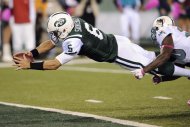 El quarterback Mark Sánchez (6), de los Jets de Nueva York, se lanza para cruzar la zona de anotación mientras el free safety Reshad Jones (20), de los Dolphins de Miami, lo trata de derribar en el segundo cuarto del partido del lunes 17 de octubre de 2011. (Foto AP/Bill Kostroun)