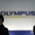 Men walk past a sign of Olympus Corp outside the company's showroom in Tokyo