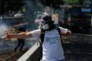 A masked anti-government protester uses a slingshot to shoot marbles at Bolivarian National guards during clashes in Caracas, Venezuela, Saturday, March 22, 2014. Two more people were reported dead in Venezuela as a result of anti-government protests even as supporters and opponents of President Nicolas Maduro took to the streets on Saturday in new shows of force. (AP Photo/Fernando Llano)