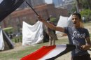 An Egyptian flag vendor waves flags in front of new erected strike tents in Tahrir Square, the focal point of Egyptian uprising in Cairo, Egypt, Saturday, June 22, 2013. Egypt's largest opposition grouping is reaching out to members of Hosni Mubarak's ruling party as it gears up for a protest campaign against the current Islamist president. (AP Photo/ Amr Nabil)