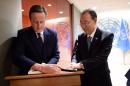 UN Secretary-General Ban Ki-moon (R) holds the pages while the British Prime Minister David Cameron signs his guest book on September 27, 2015 at the United Nations in New York