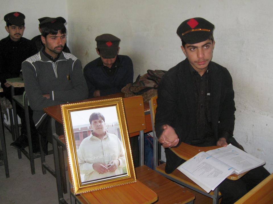 Pakistani students sit next to a picture of 17-year-old classmate Aitzaz Hasan, who residents and police say died this week while trying to stop a suicide bomber who was targeting his school in a remote village in Hangu, Pakistan, Friday, Jan. 10, 2014. Police said a teacher at the school told investigators that he saw Hasan chasing the attacker and then saw the attacker detonate the bomb that killed the teen. Local resident Miqdar Khan said people in the violence-prone district were hailing the teen as a hero.(AP Photo/Abdul Rehman)