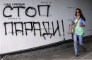 A woman walks past a graffiti reading, "Stop the parade" in Belgrade