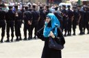 A woman waits as security personnel close off a street leading to Al-Azhar mosque when Egypt's President Mohamed Mursi is in it performing the Al-Gomaa prayer in Cairo