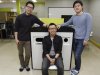 In this Tuesday, May 14, 2013 photo, from left, Ecube Labs CEO Kwon Sunbeom, his co-founders Lee Seungjae and Kwon Hyungsuk pose with their product, a solar energy-powered garbage bin, at their office in Seoul, South Korea. Instead while his peers were seeking jobs at Samsung and LG, Kwon Sunbeom scaled back his studies and started the company with friends. Together they invented the garbage bin that compresses rubbish using solar power and wirelessly communicates to be collected when full. Using 50 million won ($44,000) of their own money and channeling the business in a garage spirit that made Silicon Valley famous, they lived for a month in a shabby factory without air conditioning, subsisting on instant noodles, to make their first prototype. So far they have sold 31 of their “Smart Bins” to universities in Seoul and another 12 to Saudi Arabia and the United Arab Emirates. (AP Photo/Ahn Young-joon)
