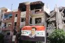 A pictures taken on a government guided tour shows a flag of Syrian President Bashar al-Assad fluttering near damaged buildings in Adra on September 25, 2014