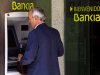 FILE - In this Friday, May 18, 2012 file photo a man uses an ATM cash point machine at a branch of the Bankia bank in Madrid. Logo says ' Welcome to Bankia'. Spain's market regulator suspended trading of shares in bailed-out Bankia on Friday May 25, 2012, ahead of a key board meeting at which the lender is expected to decide how much more rescue money it needs from the government. (AP Photo/Daniel Ochoa de Olza, file)