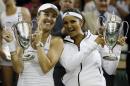 Martina Hingis of Switzerland, left, and Sania Mirza of India hold their trophies after winning the women's doubles final against Ekaterina Makarova of Russia and Elena Vesnina of Russia at the All England Lawn Tennis Championships in Wimbledon, London, Saturday July 11, 2015. (AP Photo/Kirsty Wigglesworth)