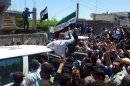 Residents shout as they gather around a vehicle carrying United Nations observers in Houla