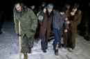 FILE - In this Saturday Feb. 21, 2015 file photo, Russia-backed separatists, some injured, walk on a snowy road in no man's land after being released by the Ukrainian military in a prisoner exchange, near the village of Zholobok, some 20 kilometers (12 miles) west of Luhansk, Ukraine. Both warring sides in eastern Ukraine are perpetrating war crimes almost daily, including torturing prisoners and summarily killing them, the Amnesty International rights group said in a report Friday May 22, 2015. (AP Photo/Vadim Ghirda, file)